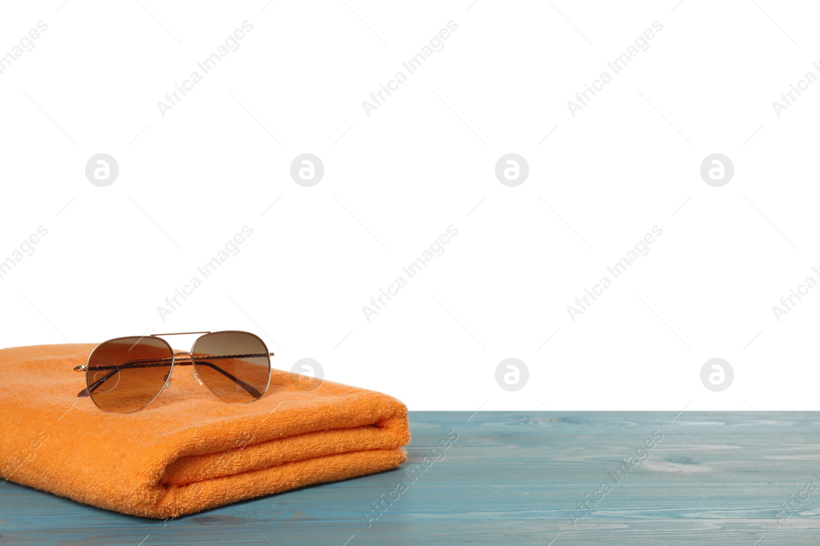 Photo of Beach towel and sunglasses on light blue wooden surface against white background. Space for text