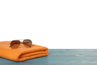 Beach towel and sunglasses on light blue wooden surface against white background. Space for text