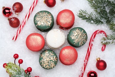 Photo of Beautifully decorated Christmas macarons, candy canes and festive decor on snow, flat lay