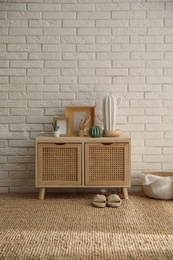 Photo of Stylish room interior with wooden cabinet near white brick wall