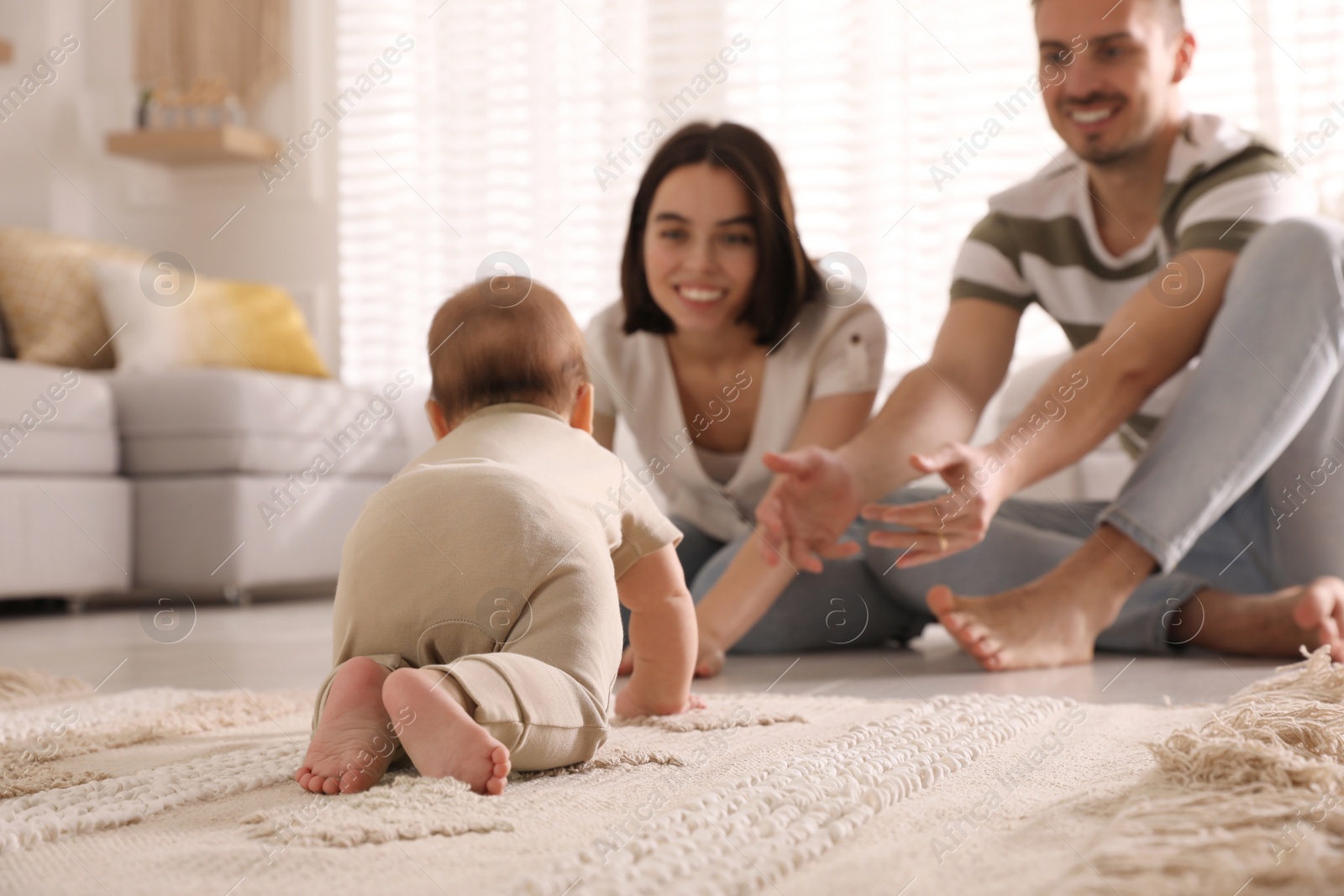 Photo of Happy parents watching their cute baby crawl on floor at home