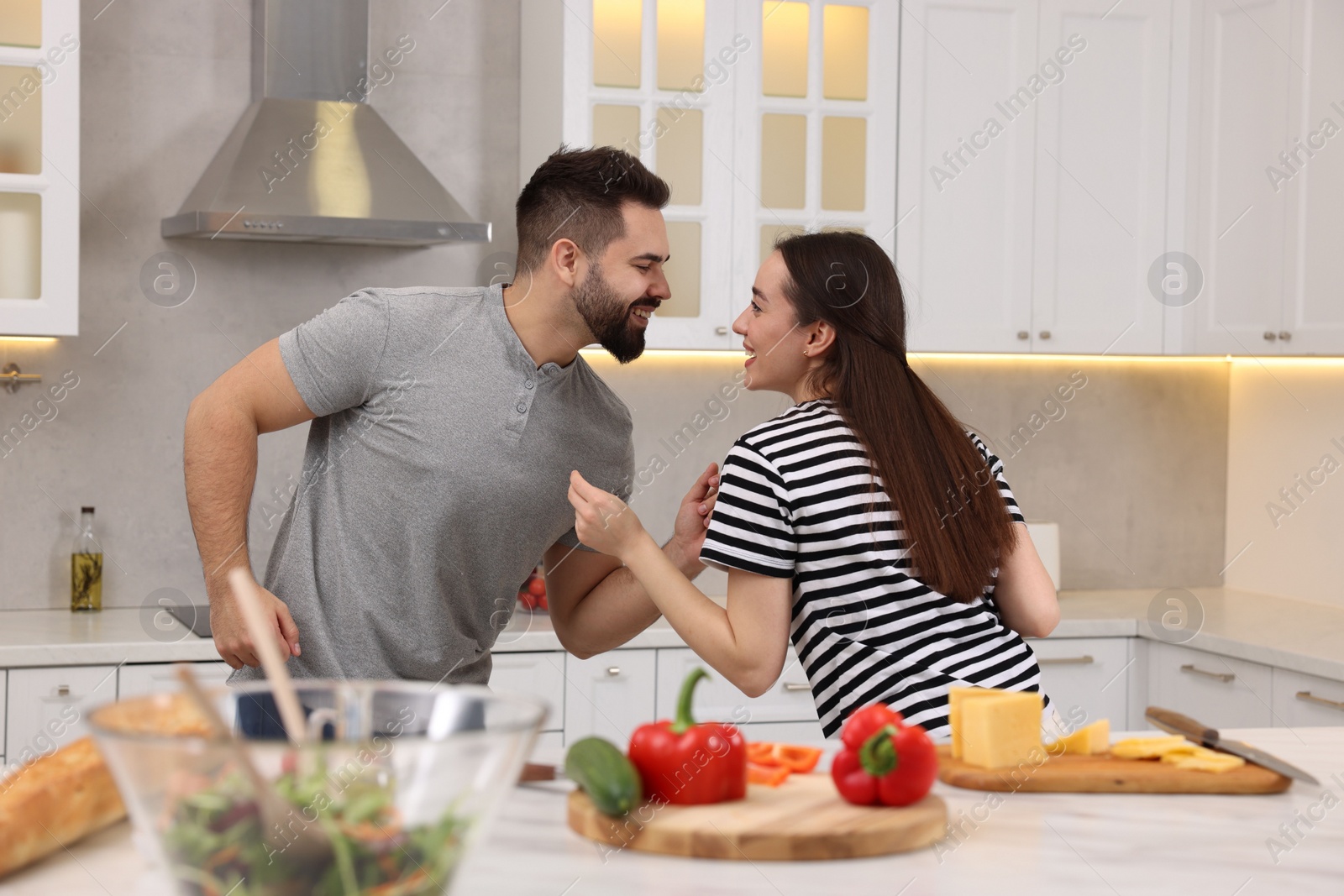 Photo of Happy lovely couple dancing together while cooking in kitchen