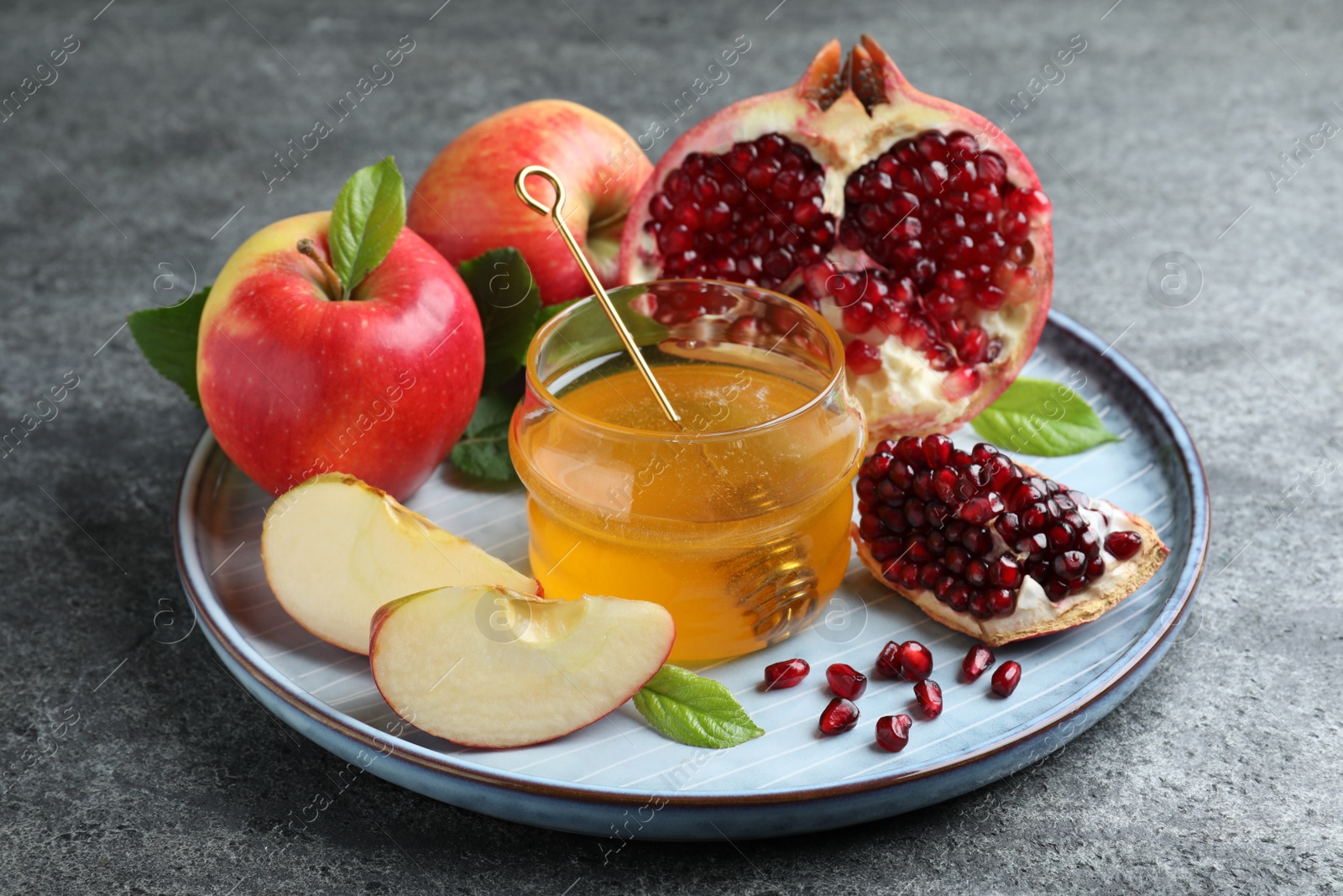 Photo of Honey, pomegranate and apples on grey table. Rosh Hashana holiday