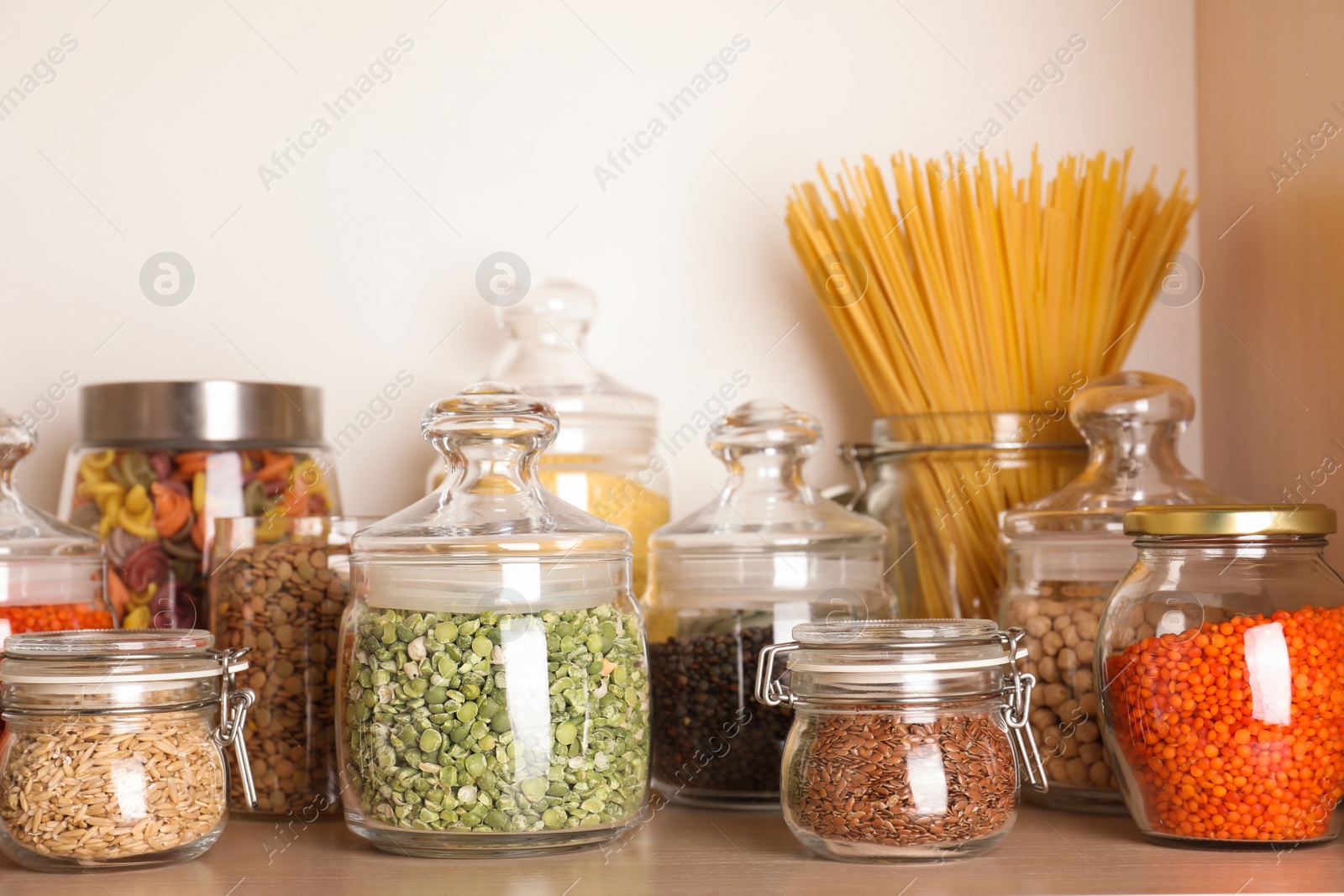 Photo of Glass jars with different types of groats on wooden shelf