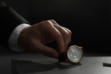 Photo of Man putting luxury wrist watch on table, closeup