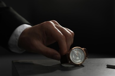 Man putting luxury wrist watch on table, closeup