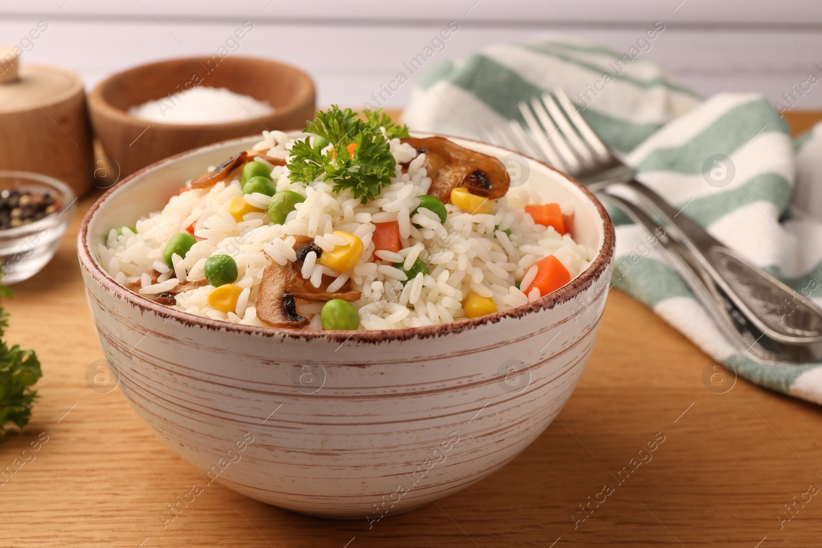 Photo of Bowl of delicious rice with vegetables on wooden table, closeup