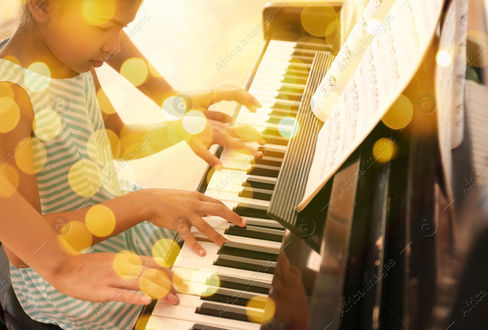 Image of Christmas and New Year music. Woman with little girl to play piano indoors. Bokeh effect