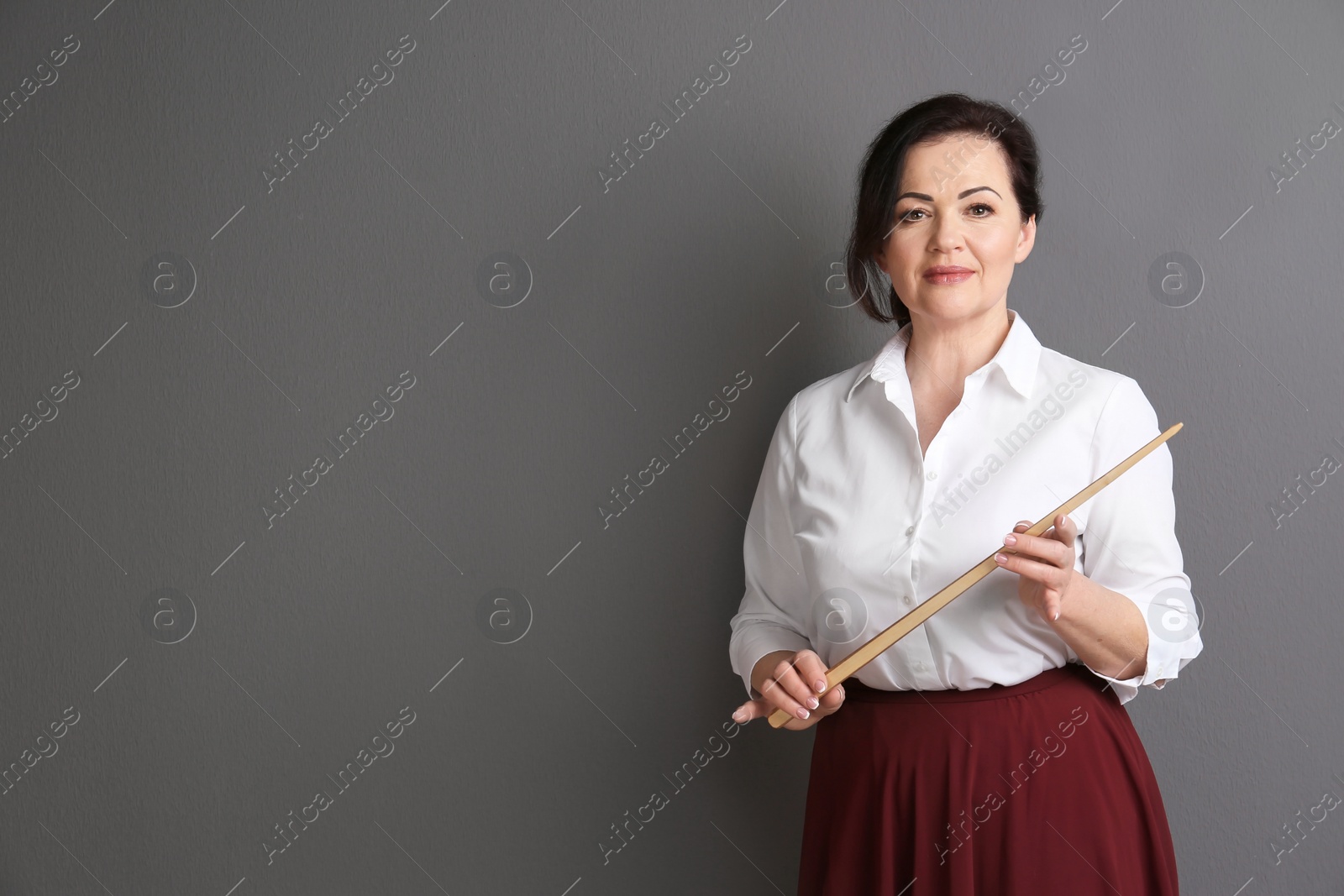 Photo of Portrait of female teacher with pointer on grey background