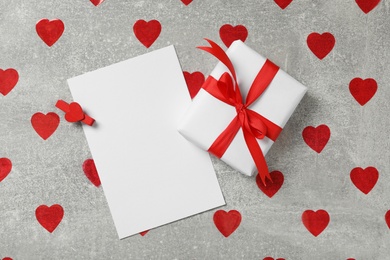 Photo of Blank card, gift box and red hearts on grey background, flat lay with space for text. Valentine's Day celebration