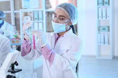 Photo of Young scientist holding test tubes with liquid samples on blurred background. Laboratory analysis