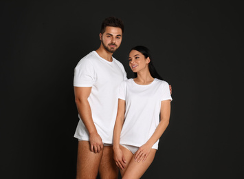 Young couple in white t-shirts and underwear on black background