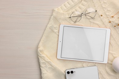 Photo of Modern tablet, glasses, smartphone and sweater on white wooden table, flat lay. Space for text