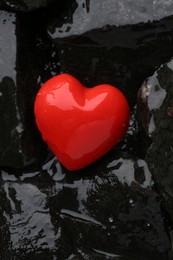 Red decorative heart on stones and water, top view