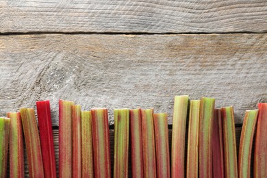 Photo of Fresh rhubarb stalks on wooden table, top view. Space for text