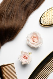 Hairdresser tools. Brown hair lock, combs, brush and flowers on white background, flat lay