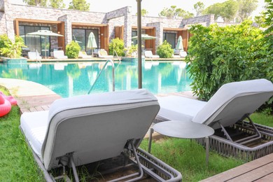 Photo of Sunbeds near outdoor swimming pool at luxury resort