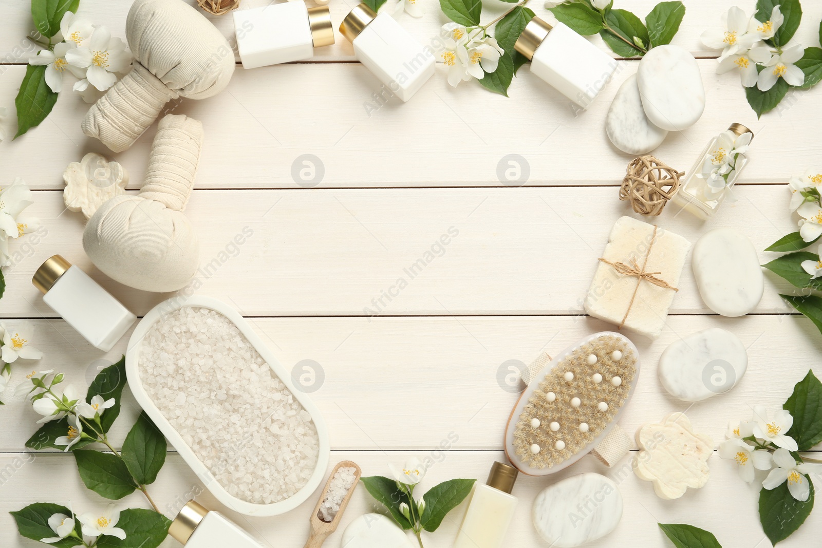 Photo of Jasmine flowers and set of spa essentials on white wooden table, flat lay. Space for text