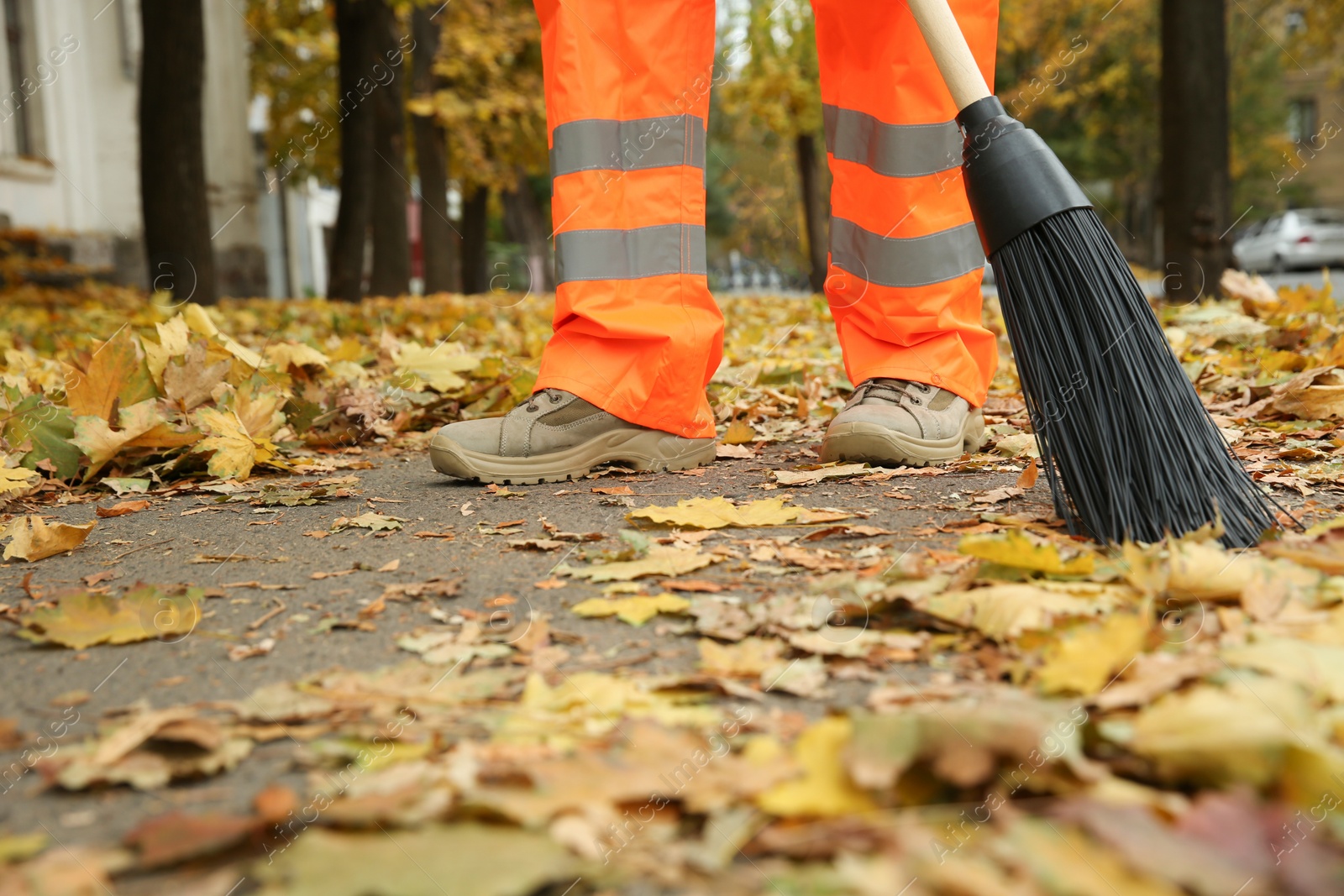 Photo of Street cleaner sweeping fallen leaves outdoors on autumn day