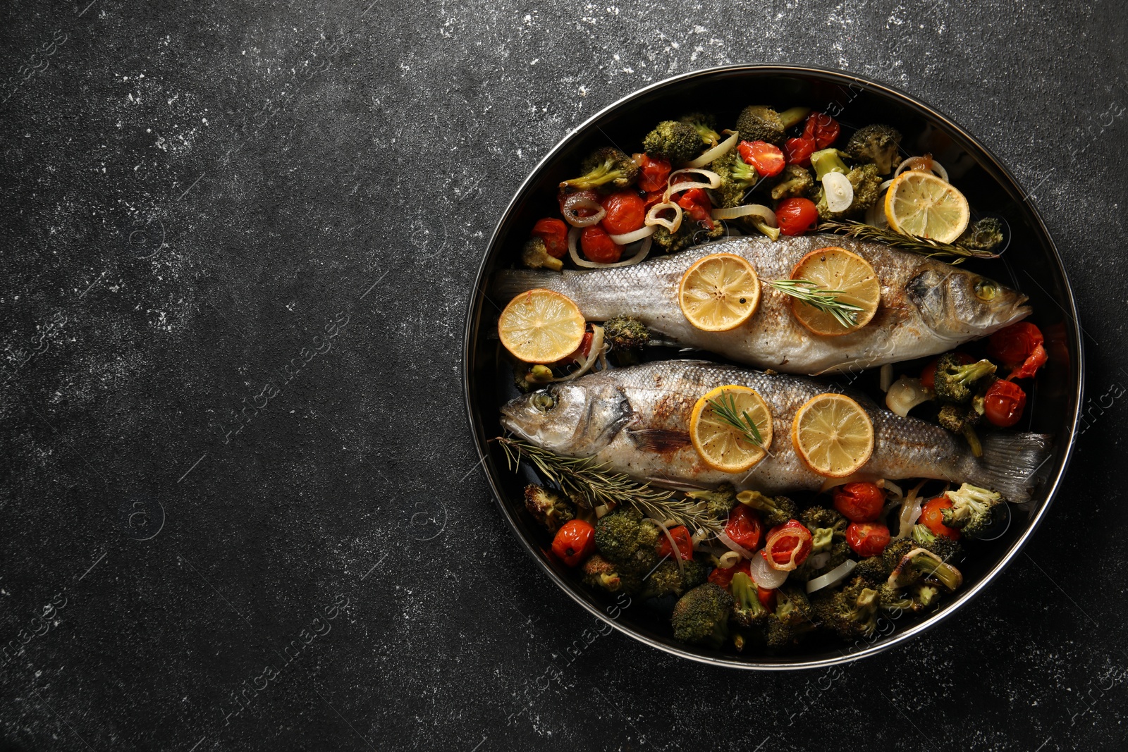 Photo of Baked fish with vegetables, rosemary and lemon on black textured table, top view. Space for text