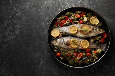 Baked fish with vegetables, rosemary and lemon on black textured table, top view. Space for text