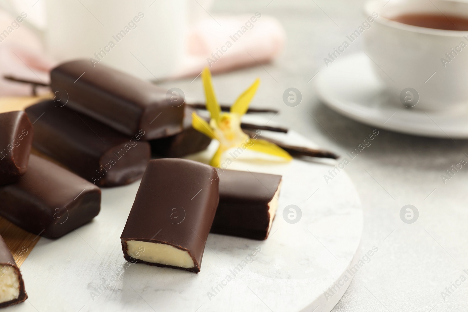 Photo of Glazed curd cheese bars, vanilla pods and flower on table, closeup. Space for text