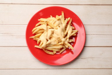 Photo of Delicious french fries with cheese sauce on wooden table, top view