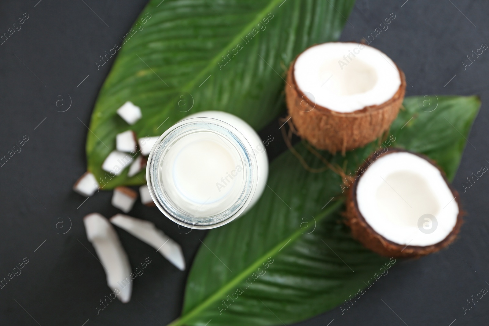 Photo of Bottle of coconut milk with fresh nuts on table, top view