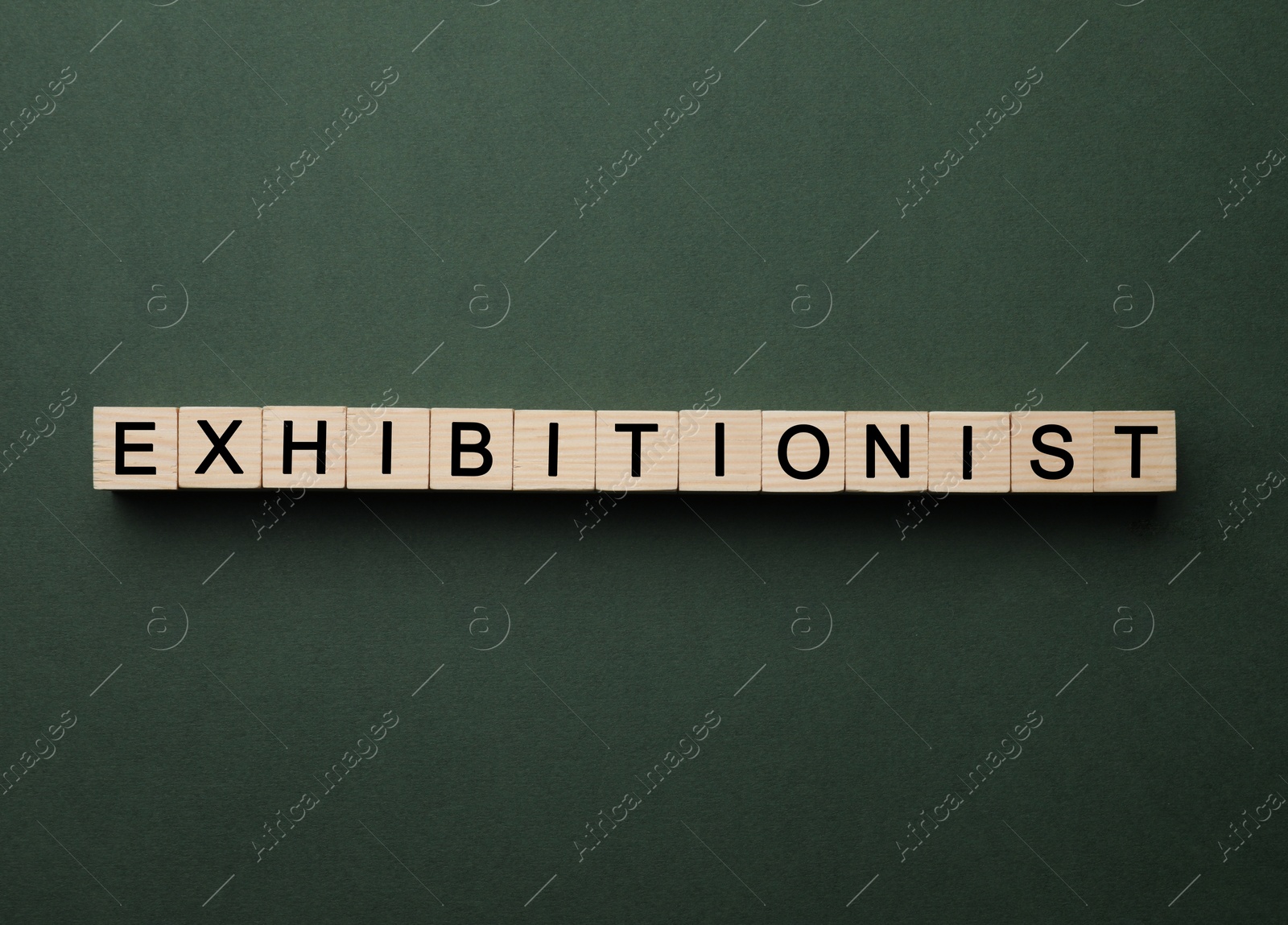 Photo of Word EXHIBITIONIST made with wooden cubes on dark green background, flat lay