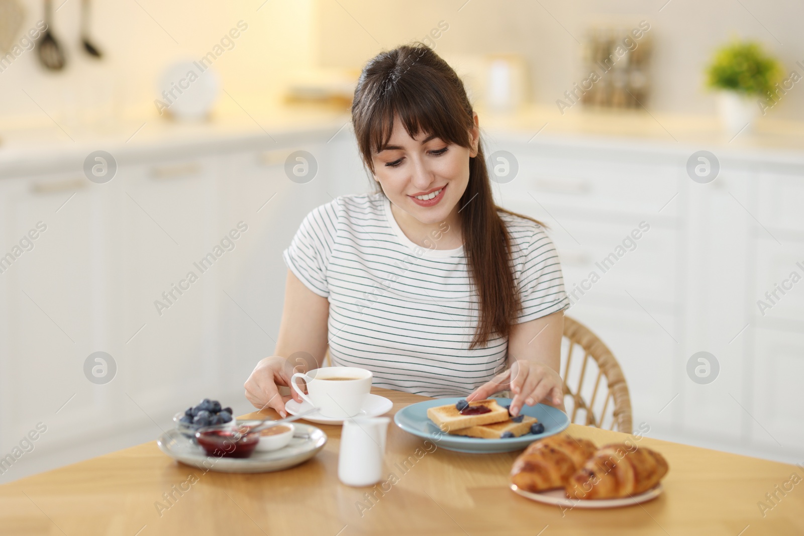 Photo of Smiling woman eating tasty breakfast at table indoors