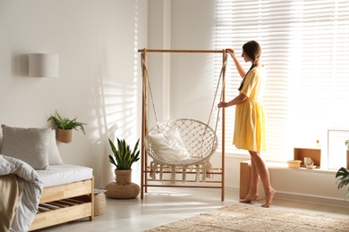 Photo of Beautiful woman near hammock chair at home