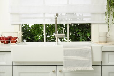 Clean towel hanging on white sink in kitchen