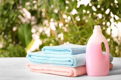 Photo of Pile of fresh towels and detergent on table against blurred background, space for text