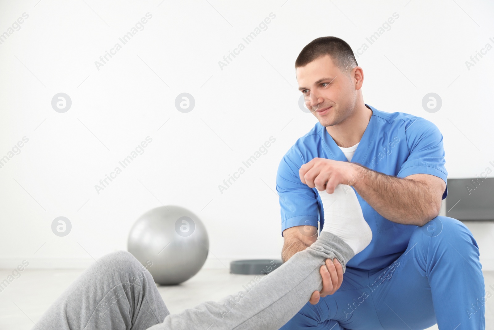 Photo of Professional physiotherapist working with male patient in rehabilitation center. Space for text