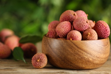 Photo of Fresh ripe lychees on wooden table outdoors, space for text