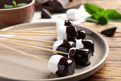 Delicious marshmallows covered with chocolate on plate, closeup