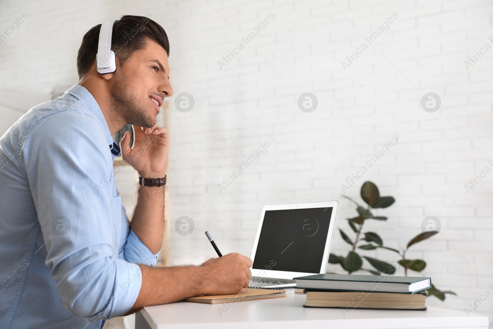 Photo of Man listening to audiobook at table with laptop