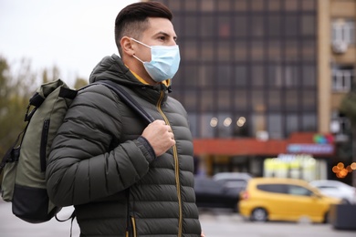 Photo of Male tourist with respiratory mask on city street. Travelling during COVID-19 pandemic