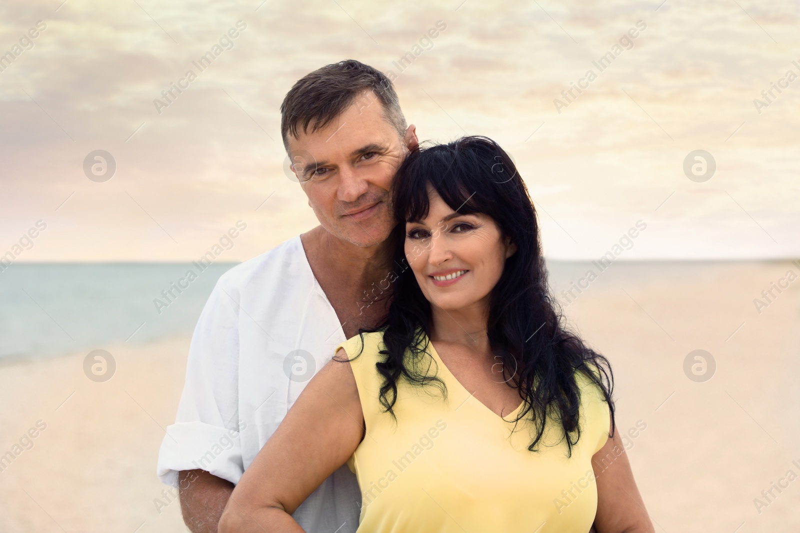 Photo of Happy mature couple spending time together on sea beach at sunset