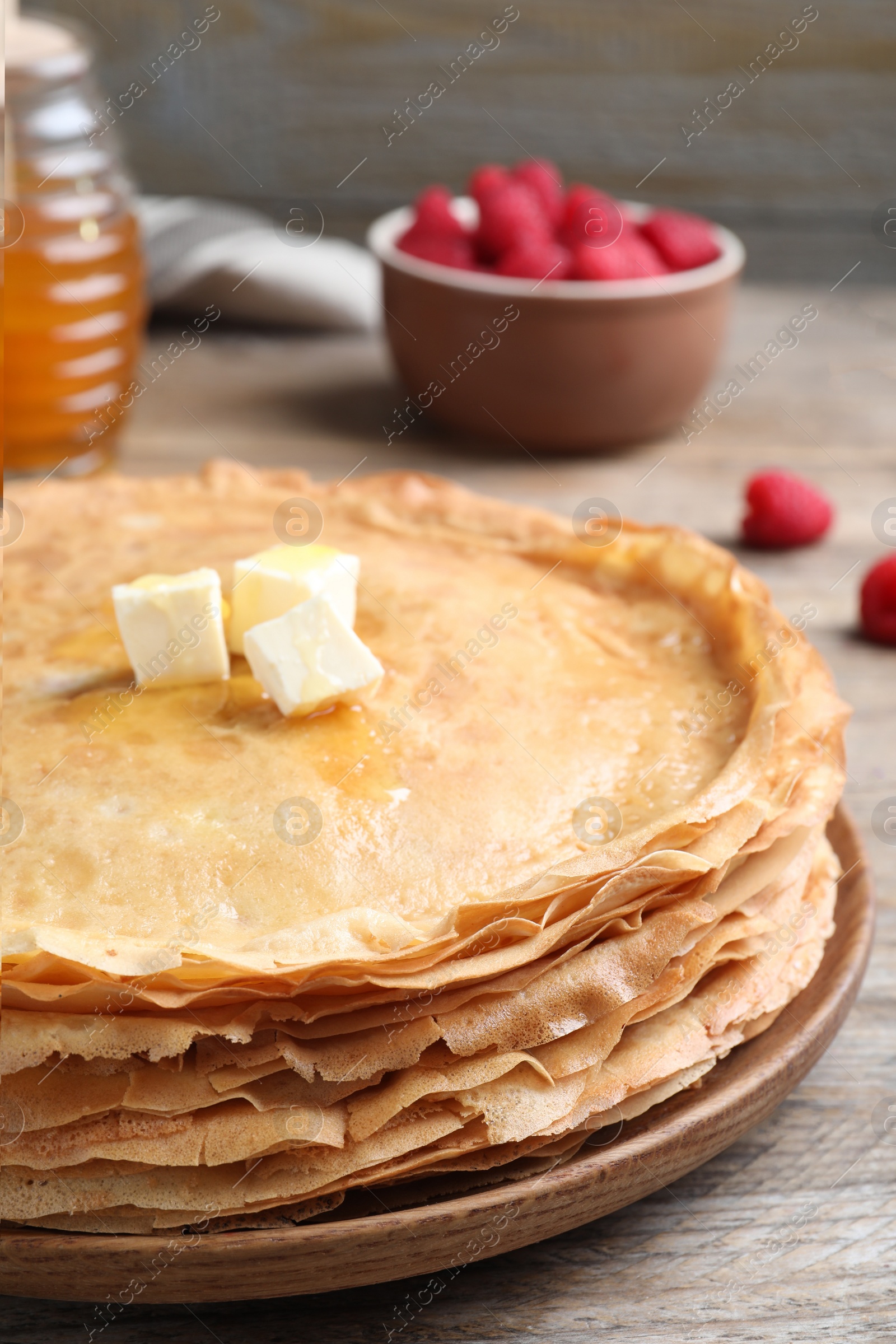 Photo of Stack of delicious crepes with melting butter on wooden table, closeup