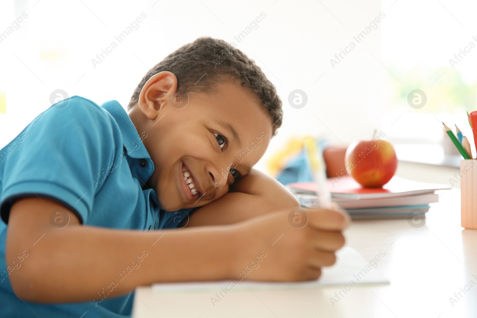 Photo of Cute little child doing assignment at desk in classroom. Elementary school