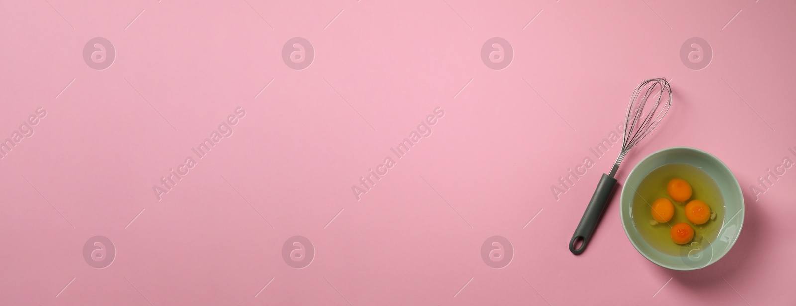 Image of Metal whisk and raw eggs in bowl on pink background, top view. Banner design with space for text