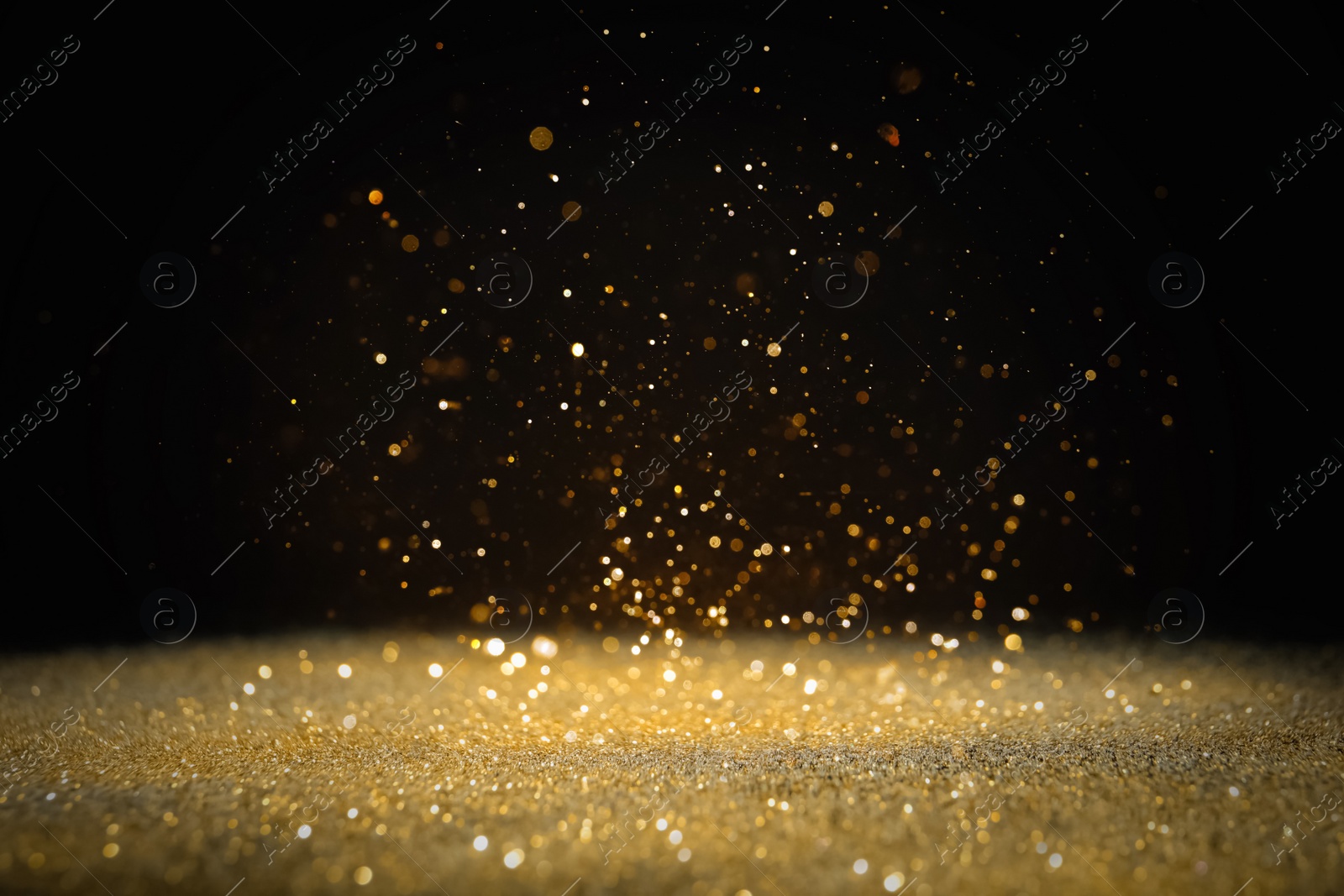 Photo of Shiny golden glitter falling down on black background. Bokeh effect