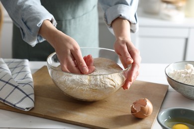 Woman kneading dough at white wooden table in kitchen, closeup