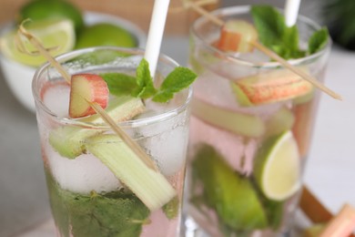 Tasty rhubarb cocktail with lime on table, closeup view