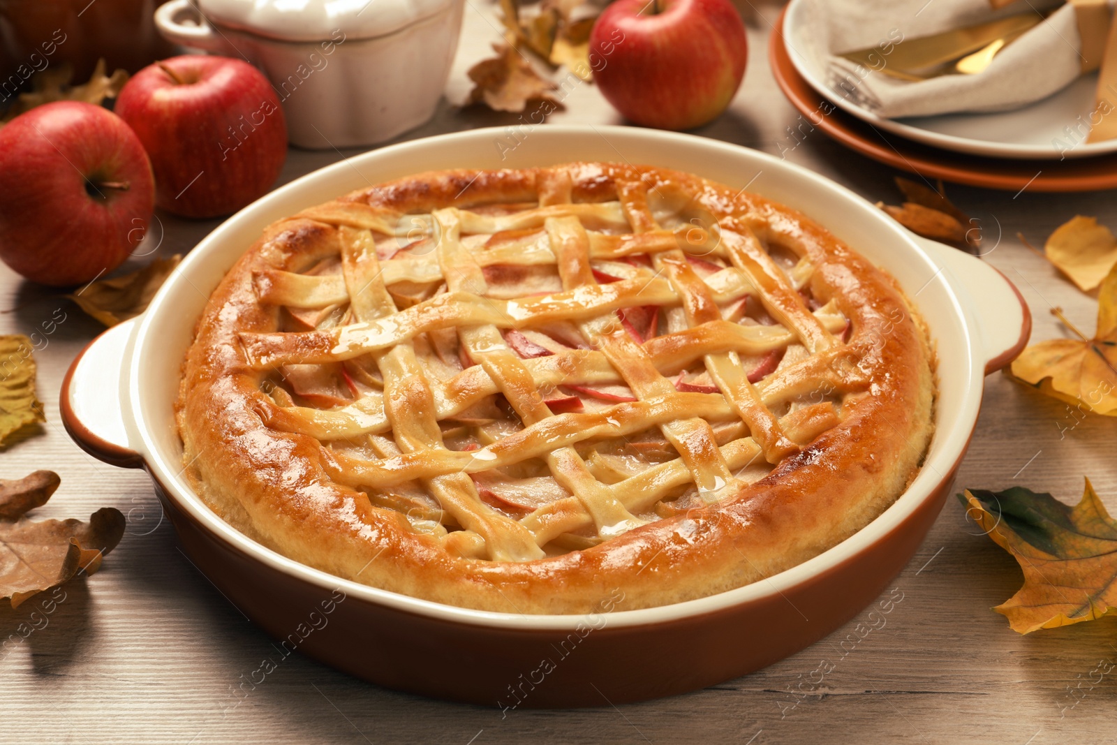 Photo of Delicious homemade apple pie and autumn leaves on wooden table. Thanksgiving Day celebration