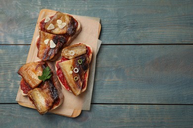 Tasty sandwiches with fried pork fatback slices on light blue wooden table, top view. Space for text