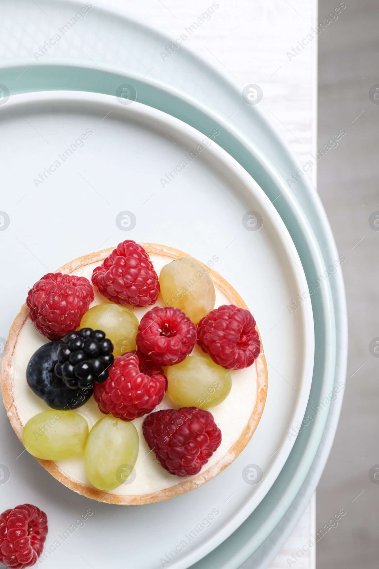 Photo of Delicious tartlet with berries on white table, top view