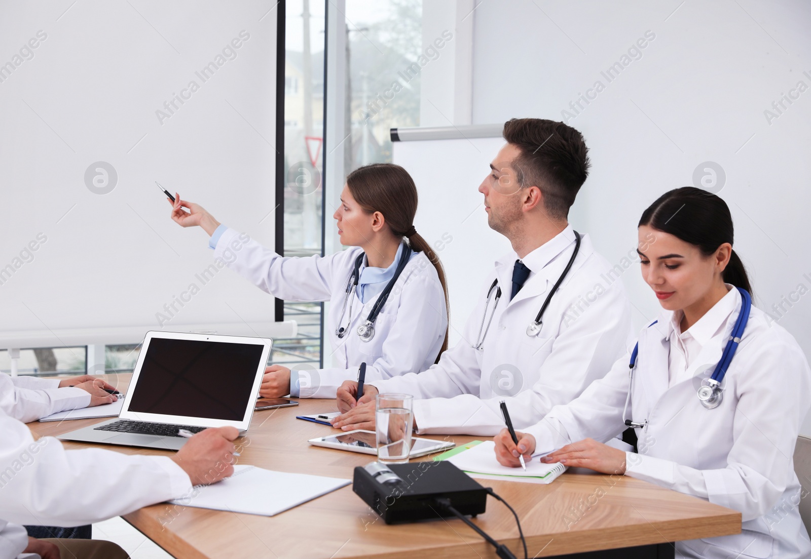 Photo of Team of doctors using video projector during conference indoors