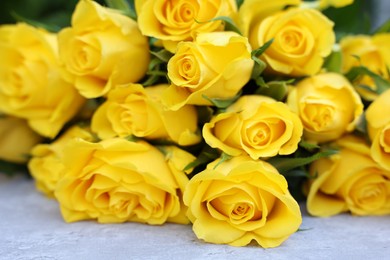 Photo of Beautiful bouquet of yellow roses on light table, closeup